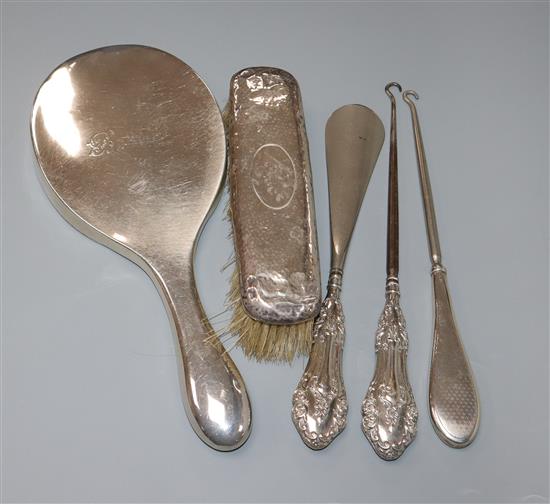 A silver backed mirror, a brush, a shoe horn and two button hooks.